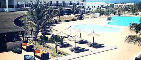 Um resort com uma piscina grande, espreguiçadeiras e vista para o oceano.