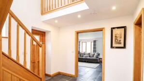A modern interior with a wooden staircase, a living area with a sofa and a rug, and a framed picture on the wall. - Cwmwr (Oswestry)
