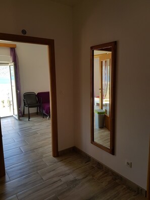 A hallway with a wooden floor, a mirror on the wall, and a door leading to another room. - Apartment Karolina (Marina)