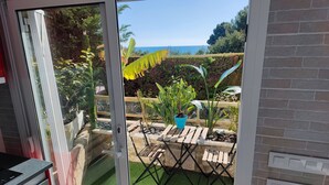 Une terrasse avec vue sur l’océan, une table en bois et une plante en pot.
