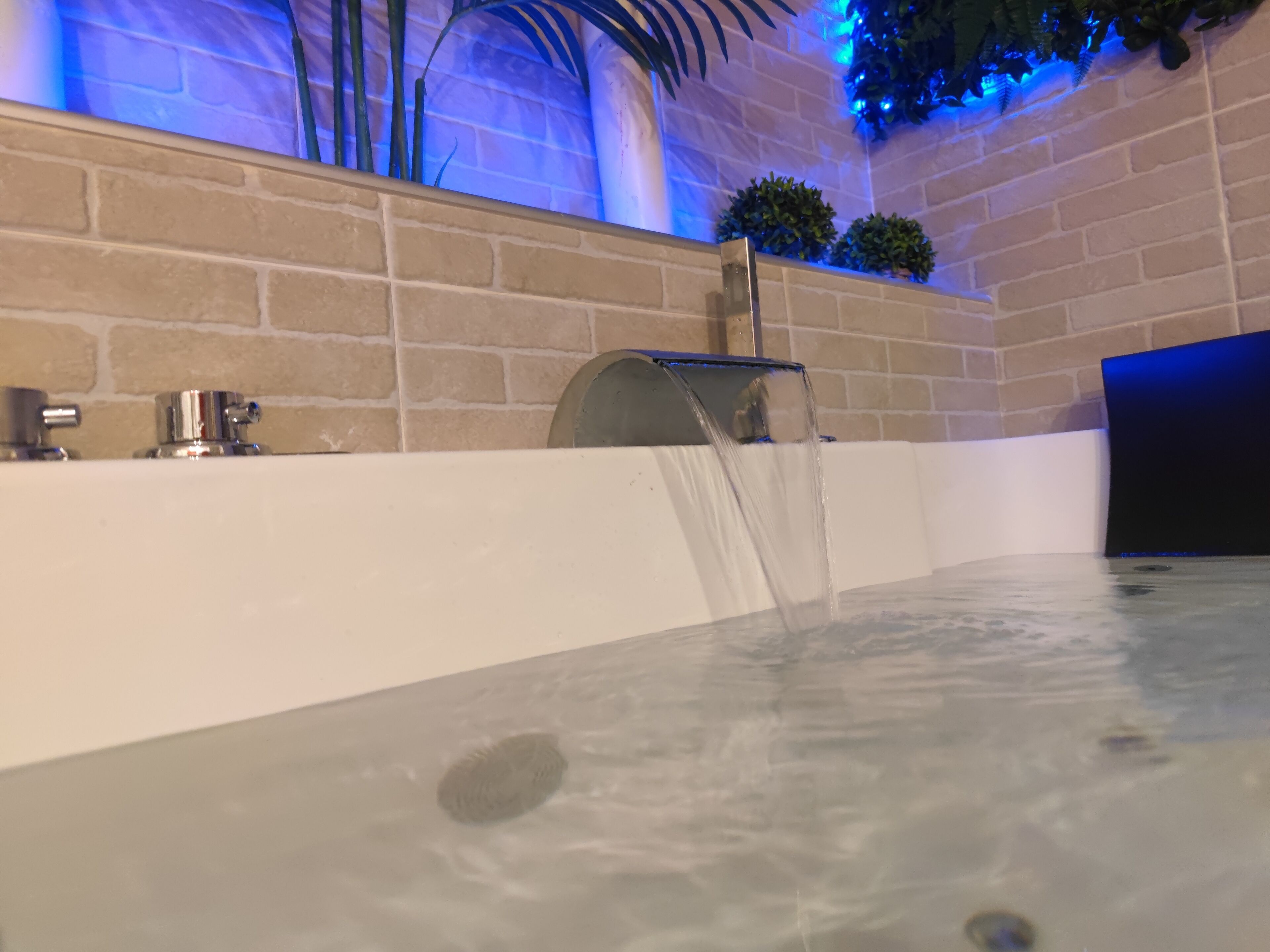 Une salle de bain moderne avec une baignoire, un robinet et une pomme de douche fixée au mur.