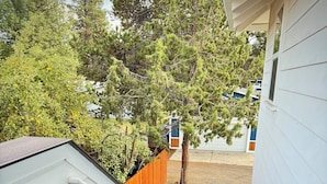 A wooden deck leading to a covered outdoor area with a view of a backyard and a garage.