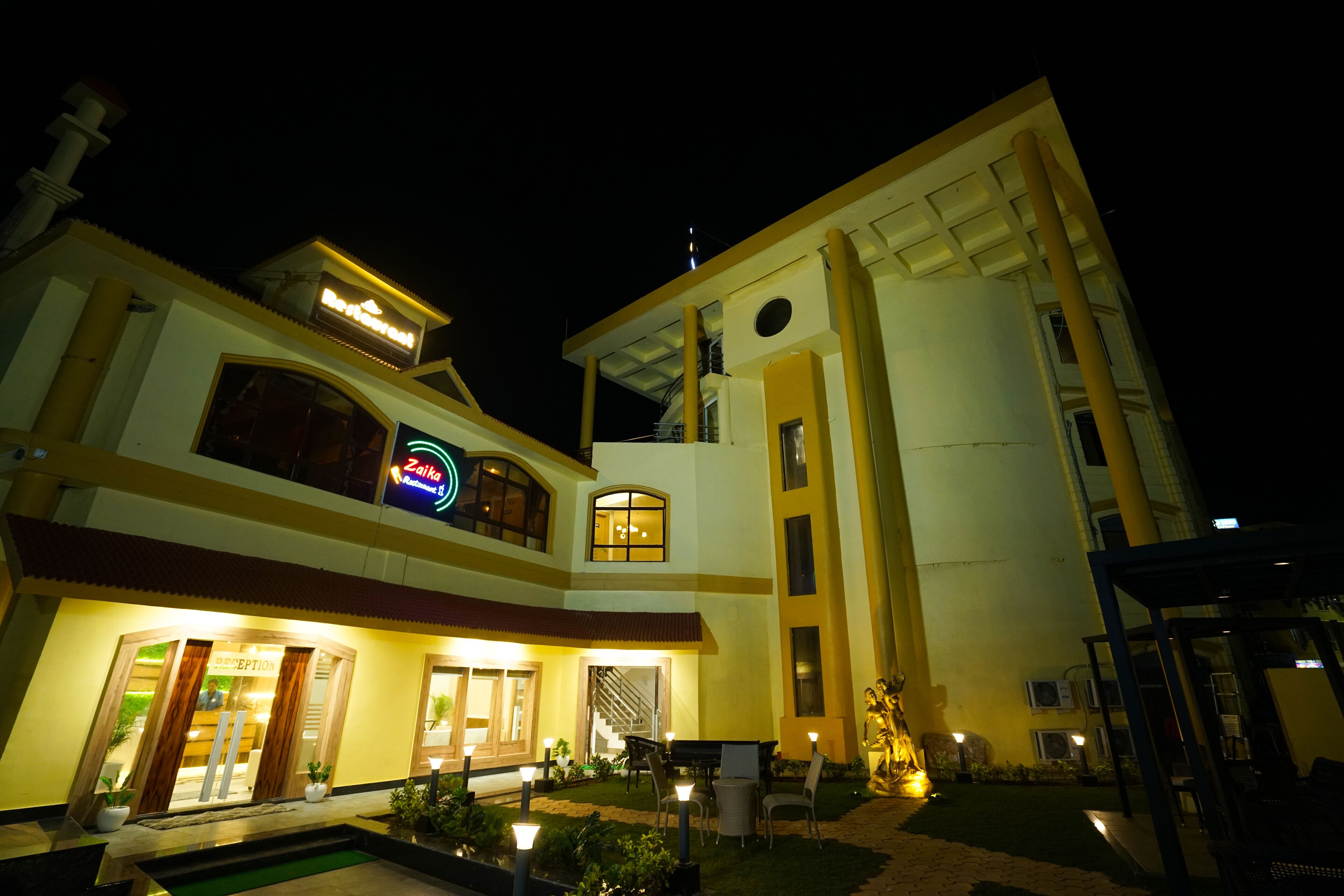 A multi-story hotel with a reception area, outdoor seating, and a pool.