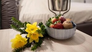 A hotel room with a bed, a metal bucket, and a bowl of fruit and flowers on a table. - Fervore Luxury Rooms (Palermo)