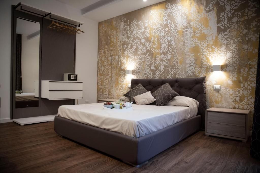 Un dormitorio moderno con una cama grande, mesitas de noche, un armario y un espejo.