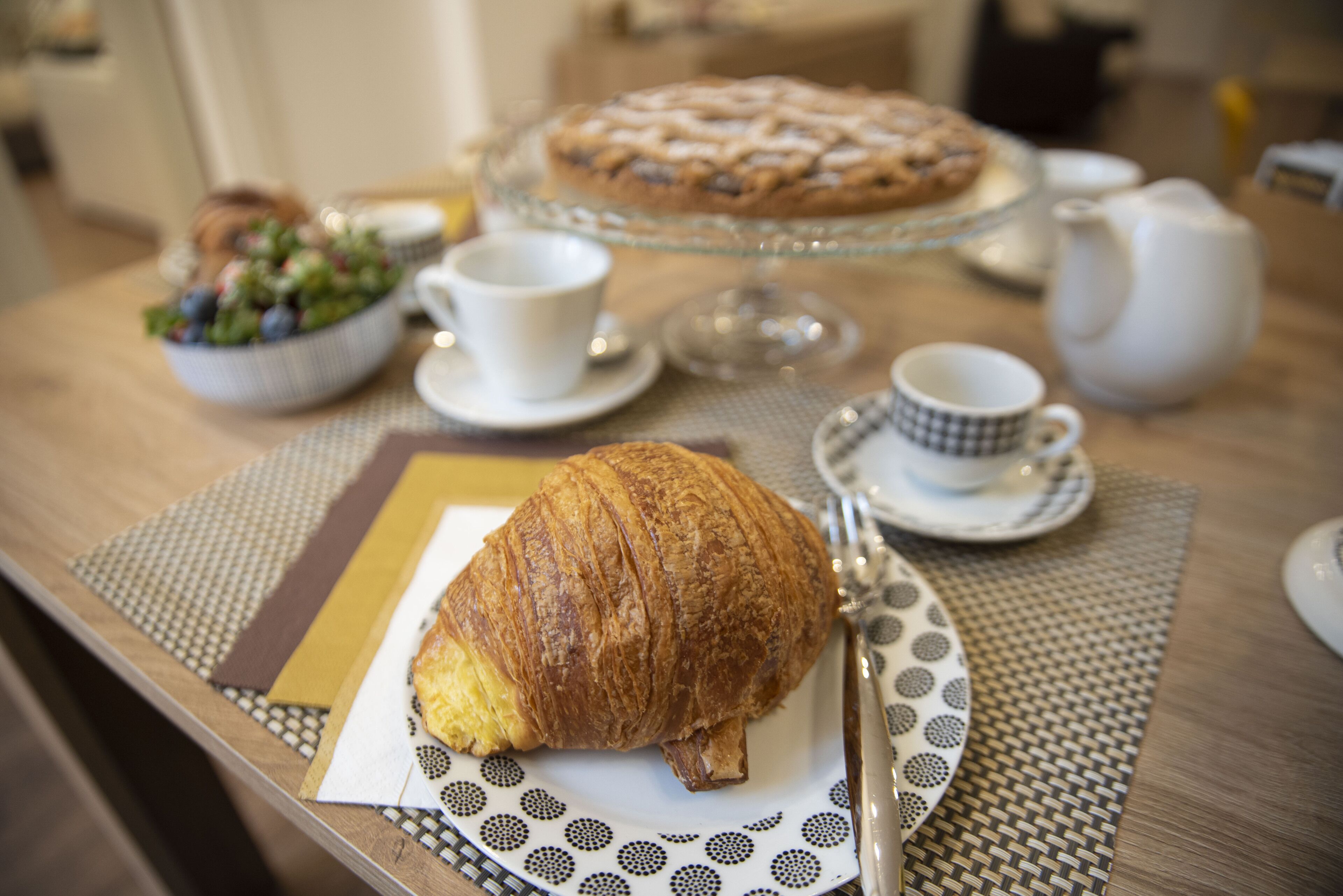 A table with a croissant, a pie, and a bowl of salad.