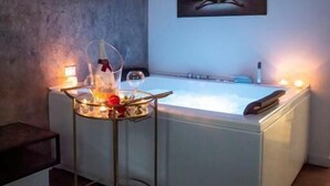 A spa room with a massage table, a small table with candles and a bottle, and a painting on the wall. - Fervore Luxury Rooms (Palermo)