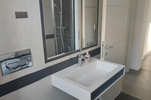 Ein Badezimmer mit Waschbecken, Spiegel und Duschkabine.
