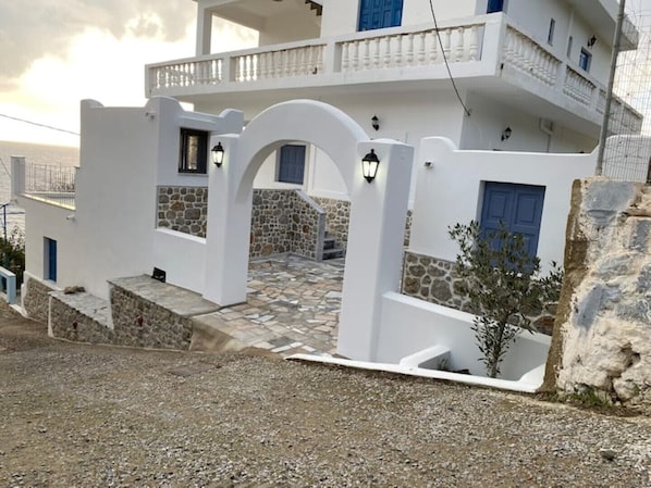 A white building with a stone facade, blue doors, and a balcony.