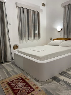 A bedroom with a single bed, a round wall clock, and a decorative rug.