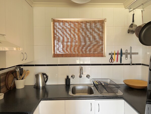 Enjoy cooking in this well-equipped kitchen with a stainless steel sink, black faucet, and ample countertop space.
