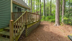 A wooden deck leading to a house with a green exterior, surrounded by a forested area. - Coastal Colonial Charm located in Ocean Pines, MD by Karsons Keys (Ocean Pines)