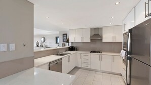 A modern kitchen with white cabinetry, a stainless steel refrigerator, and a built-in dishwasher.