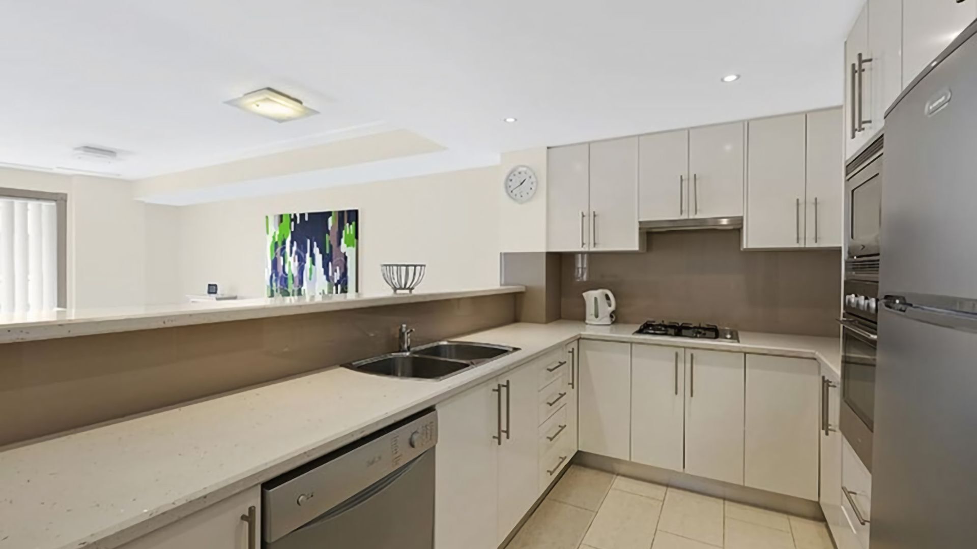 A modern kitchen with white cabinets, a stainless steel sink, a gas stove, and a built-in dishwasher.
