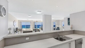 A modern kitchen with a large island, a built-in oven, and a sink.