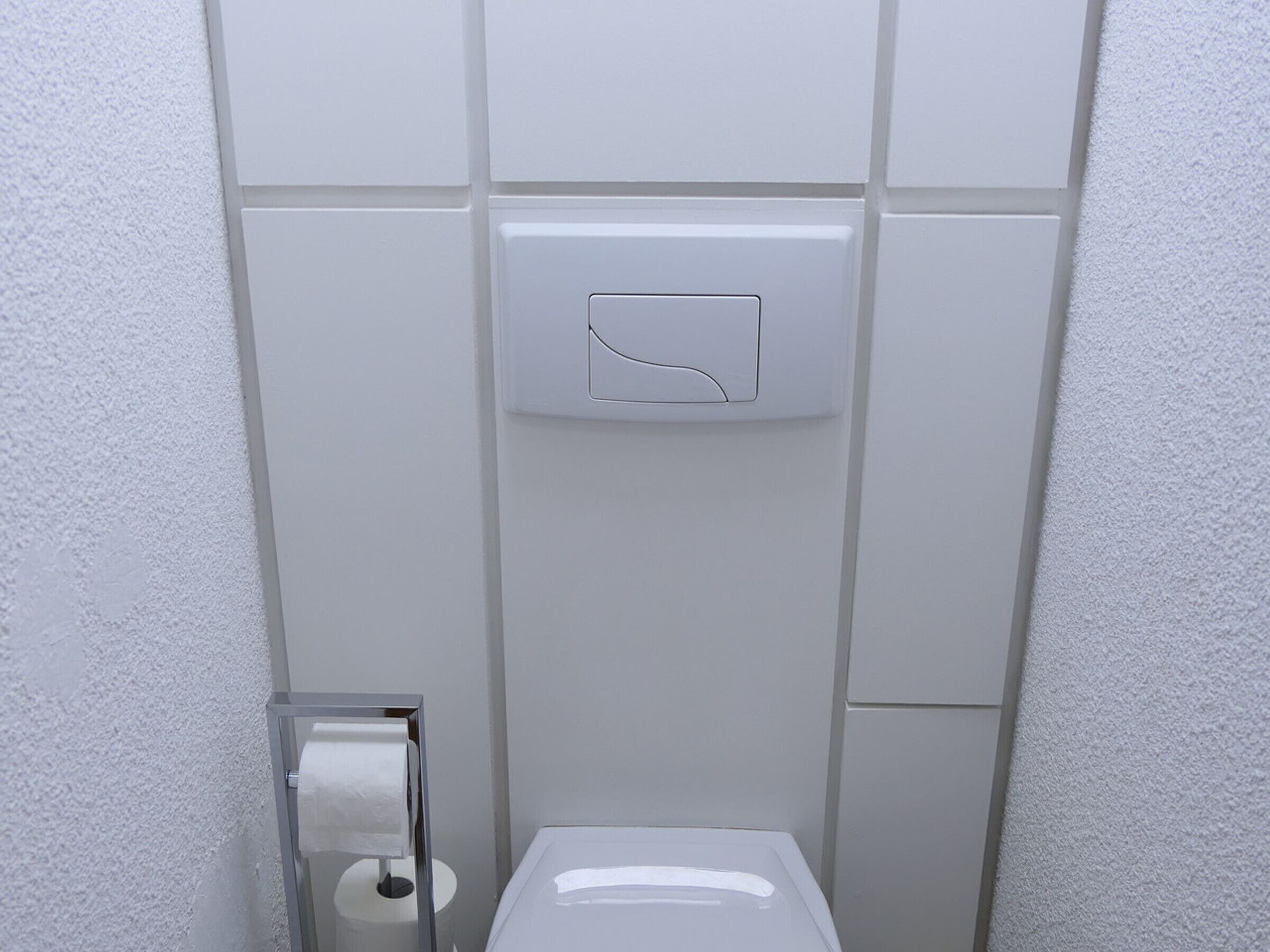 A bathroom with a toilet, a paper towel dispenser, and a hand dryer.