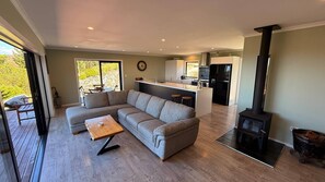 Een moderne woonkamer met een hoekbank, een houten salontafel en een open haard.