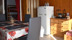 A compact kitchen with a white refrigerator, wooden cabinets, and a dining area with a table set for two.