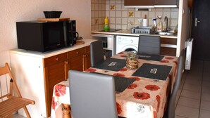 A compact kitchen with a microwave, sink, and a small dining area with a table and chairs.