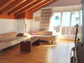 A living room with a wooden ceiling, a sofa, a coffee table, and a balcony with a railing. - Dorfstrasse 53a / 2 Appartement/Fewo 6-Bettwohnung by Interhome (Engelberg)