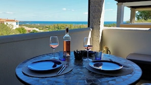 A table set for two with wine glasses and a bottle, overlooking a scenic view.