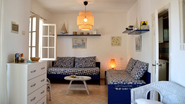 A cozy living room with a sofa, a chair, a small table, and a hanging light fixture.