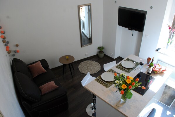 A modern living room with a black sofa, a round coffee table, and a dining area with a white table set for two. - Loge Saint Nicolas, Beaune town center (Beaune)