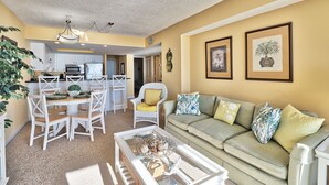 A living room with a sofa, coffee table, and dining area with chairs and a table.