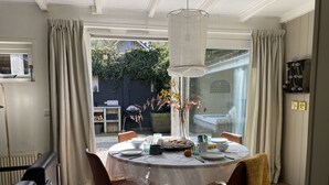 A dining area with a round table, chairs, and a view of the garden through a glass door.