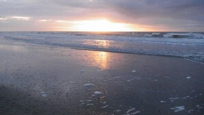 A beach at sunset with waves approaching the shore.