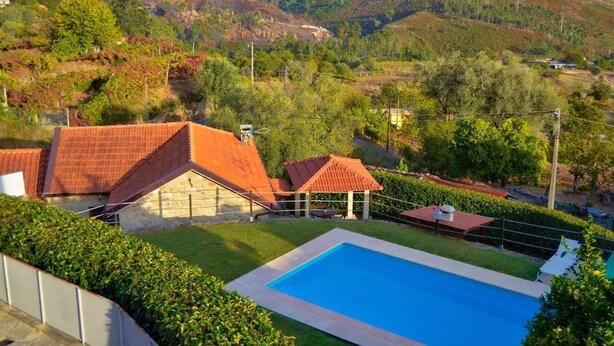 Una zona residencial con piscina, edificios de piedra y un paisaje montañoso al fondo.