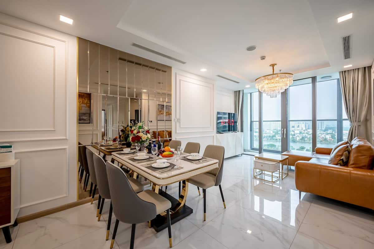 Uma sala de jantar moderna com uma mesa grande, cadeiras e um candelabro.