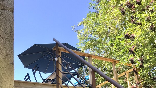 A wooden staircase with metal railings, leading to a covered outdoor seating area with umbrellas.