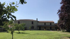 A two-story building with a tiled roof, surrounded by a well-maintained lawn and a few trees.