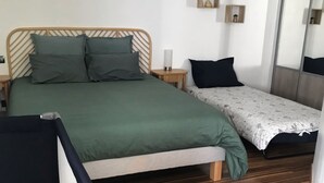 A bedroom with a bed, a bedside table, a small table, a chair, and a mirror.