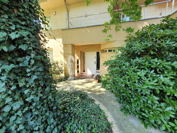 A courtyard with a statue, a wooden door, and lush greenery.