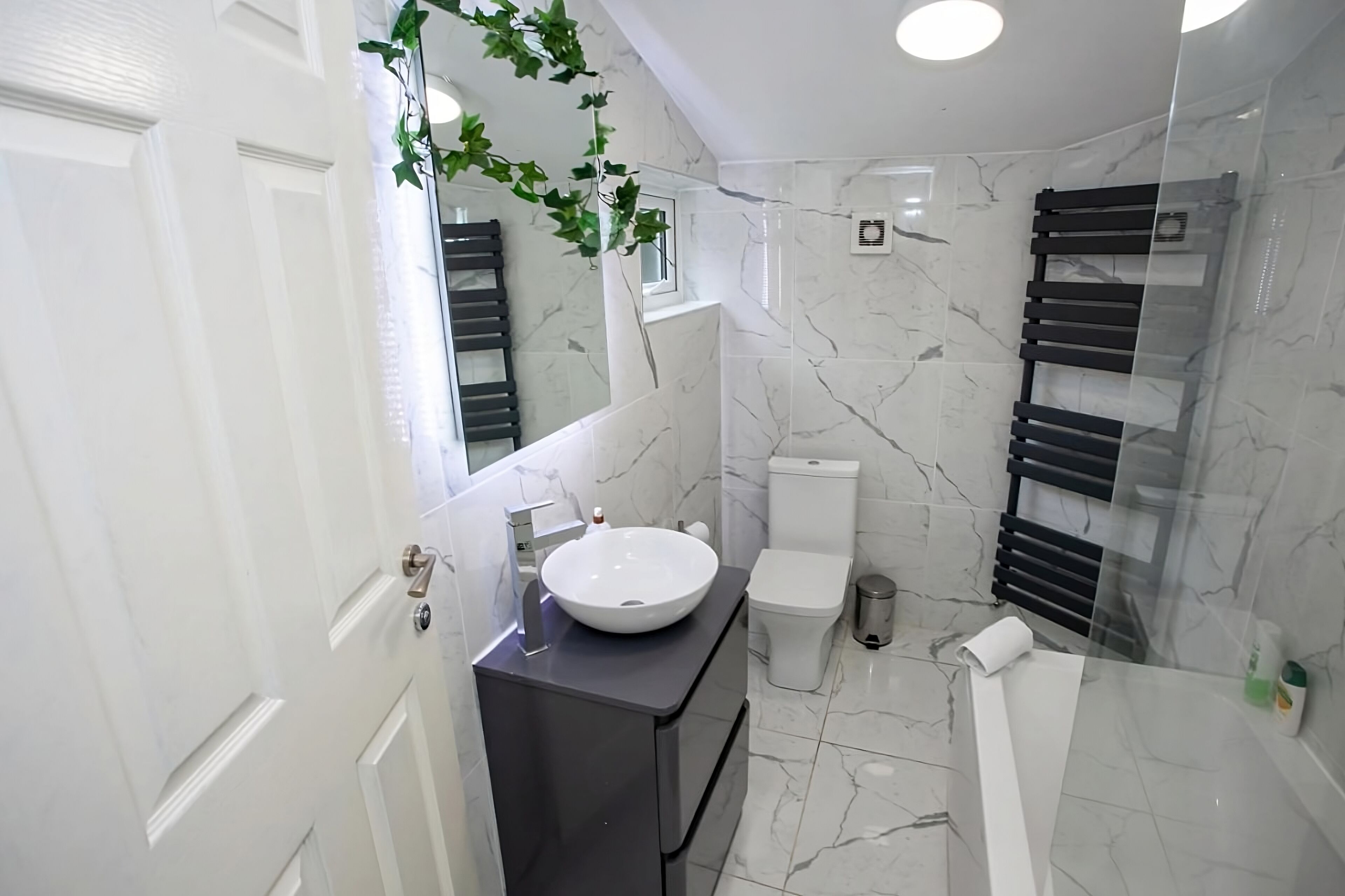 Un bagno moderno con lavandino, water e doccia bianchi.