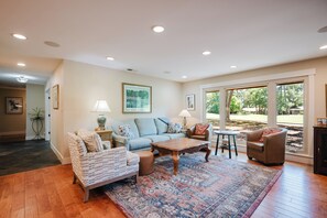 A living room with a sofa, armchairs, a coffee table, and a rug.