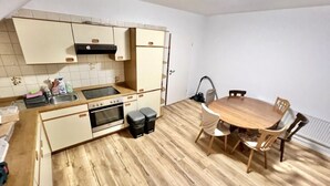 Une cuisine compacte dotée d’un plan de travail en bois, d’un four encastré et d’une table à manger avec des chaises.