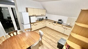 Une cuisine de taille réduite, dotée de meubles de rangement en bois, d’une table à manger et d’un petit réfrigérateur.