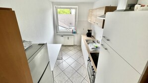 Une cuisine de taille réduite, avec des meubles blancs, une fenêtre et une vue sur l’extérieur.