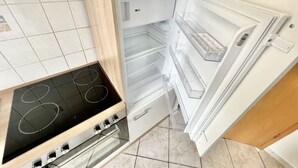 Une cuisine équipée d’une cuisinière intégrée et d’un réfrigérateur blanc doté de plusieurs étagères.