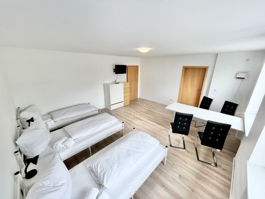 A room with three beds, a desk, and a chair.
