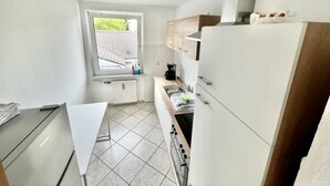 Une cuisine de taille réduite avec des meubles blancs, une fenêtre et une vue sur l’extérieur.
