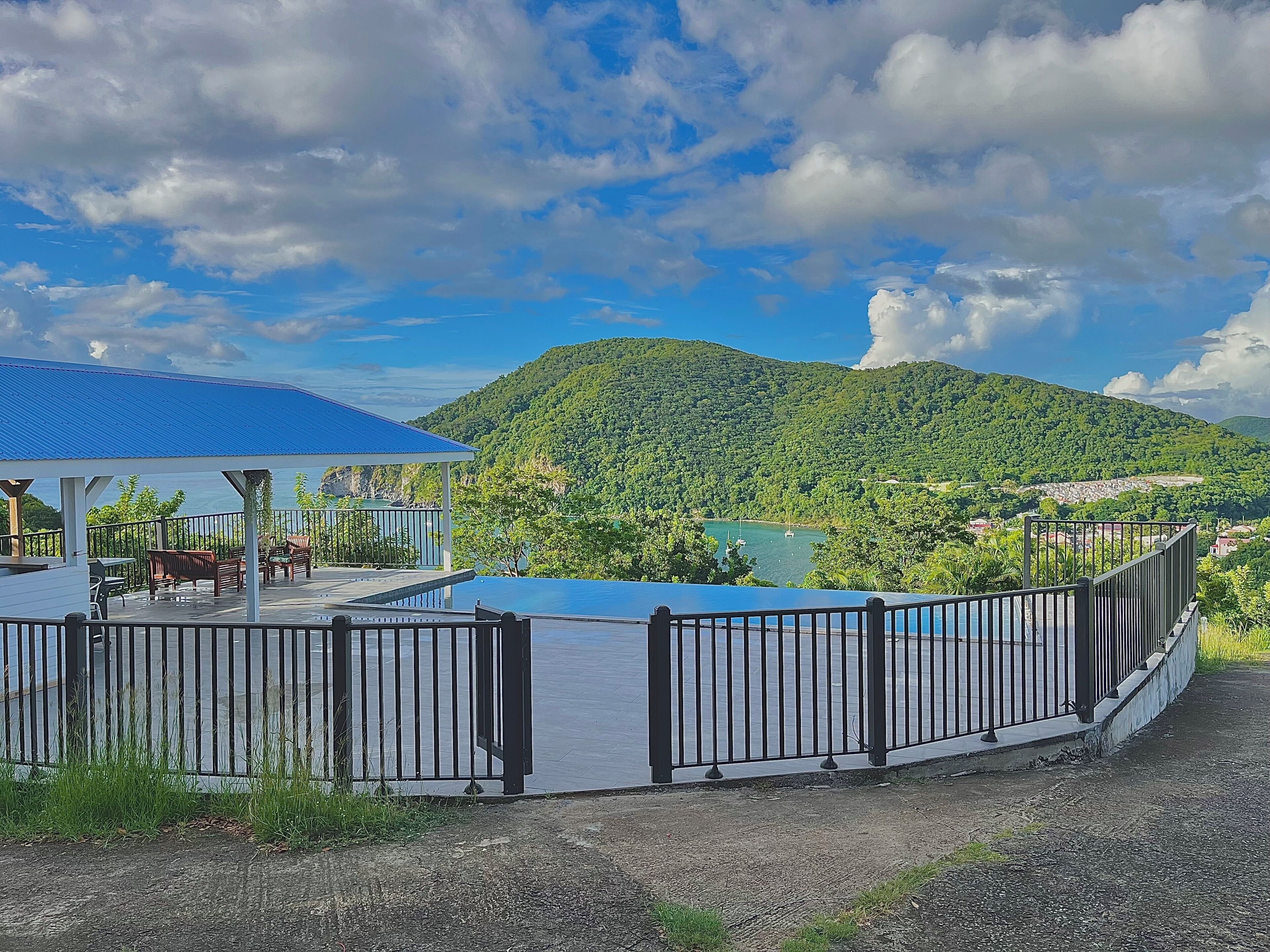 A covered outdoor area with a pool, a fenced deck, and a view of a lake and mountains.