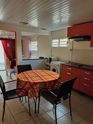 Une cuisine de taille réduite avec une table ronde, des chaises, un lave-linge et un meuble rouge.
