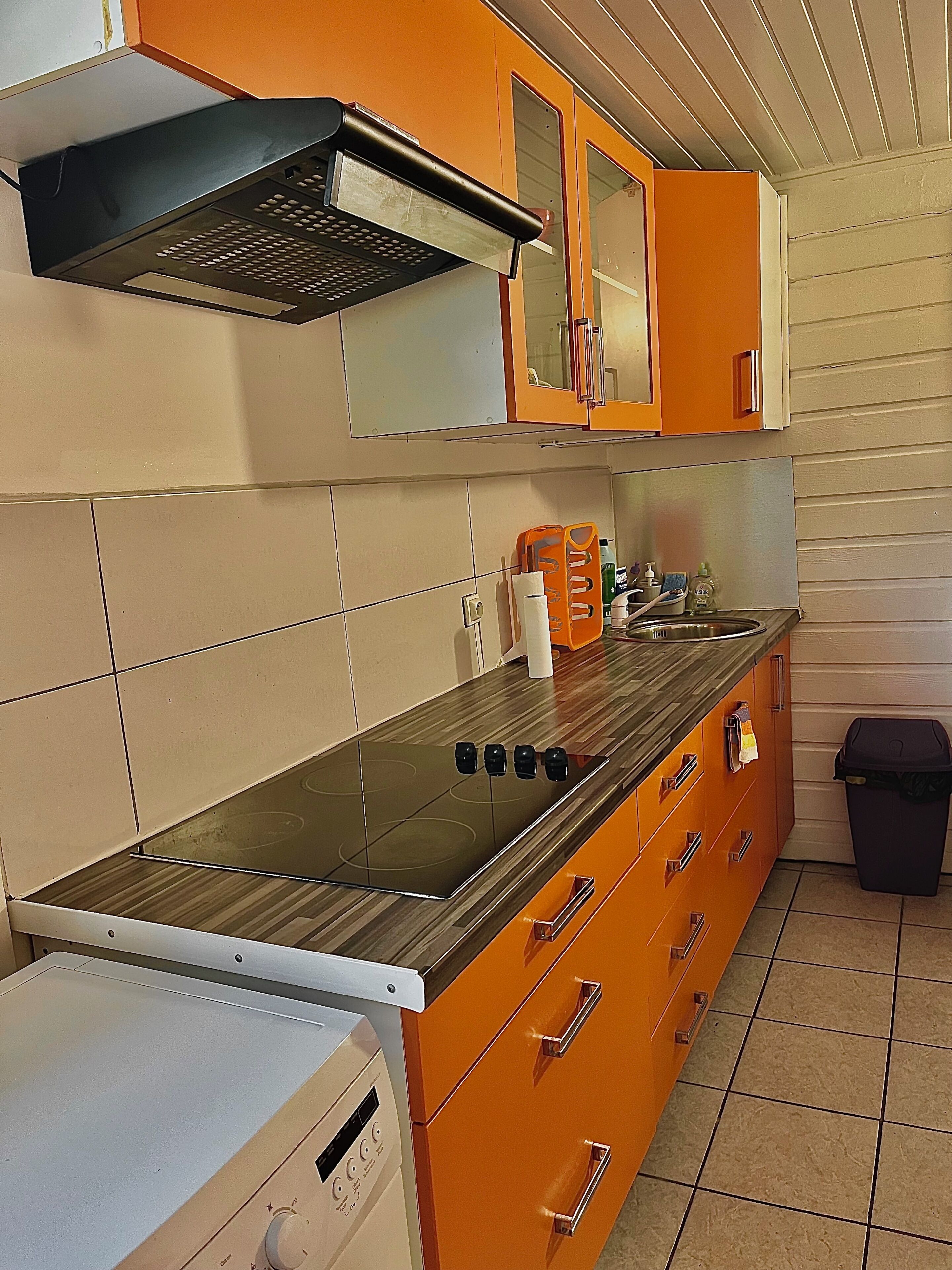 Une cuisine équipée d’une cuisinière, d’un four, de placards et d’une poubelle.