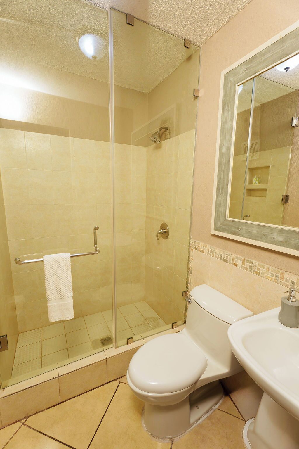 Un baño con ducha acristalada, inodoro y lavamanos.