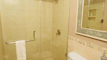 Un baño con ducha acristalada, inodoro y lavamanos.