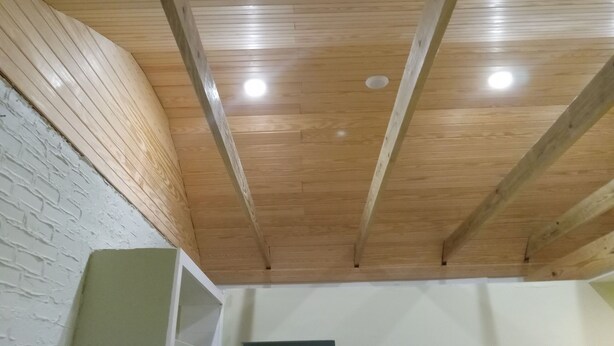 Ein Zimmer mit Holzboden, sichtbaren Balken und einer weißen Ziegelwand.